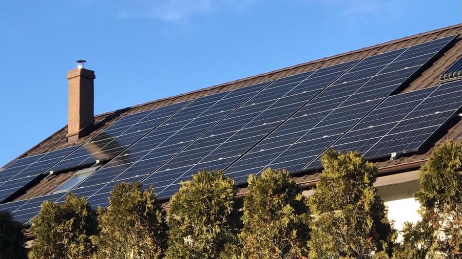 Panouri fotovoltaice montate pe acoperișul unei case, printre copaci